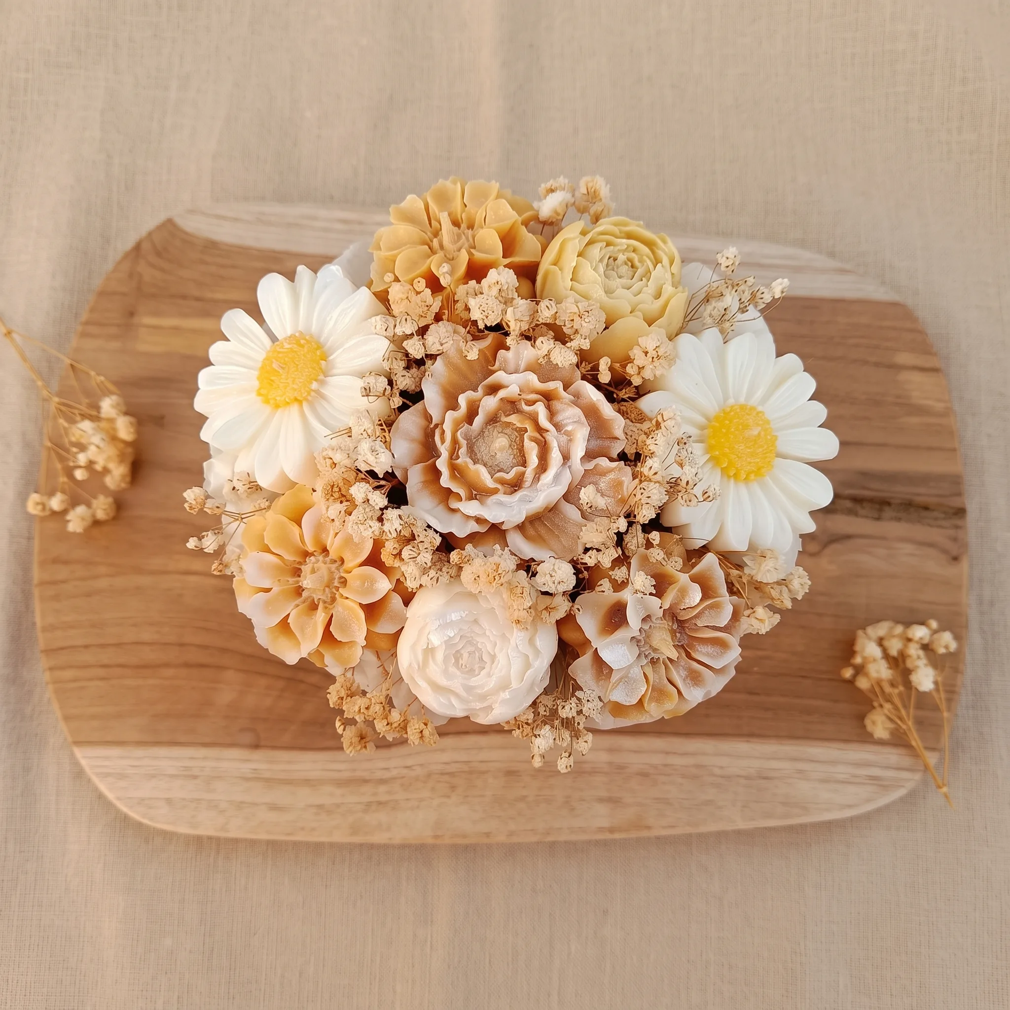 Bouquet de fleurs en cire aux tons crème et caramel, posé sur une planche en bois